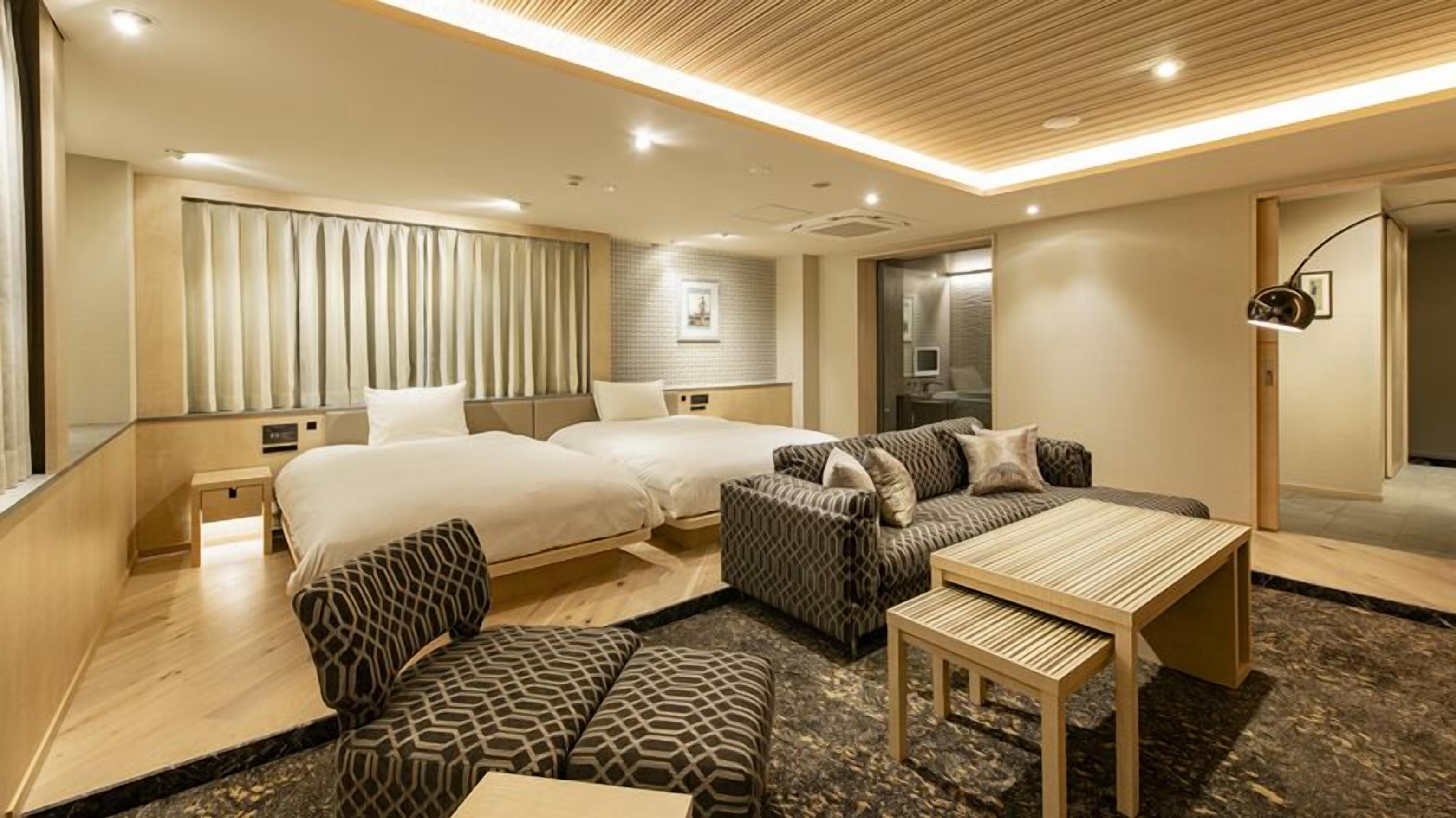 A hotel room with two beds, a sofa, a table, and a TV.