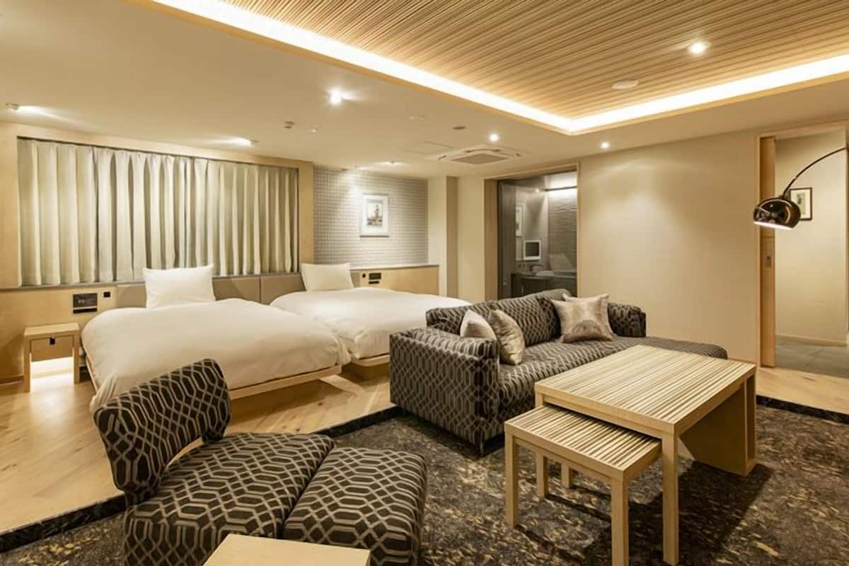 Ett hotellrum med två sängar, en soffa, ett bord och en tv.