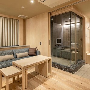 A modern interior with a sofa, a table, and a glass-enclosed shower area. - Terrace Hotel f Shinosaka (Osaka)