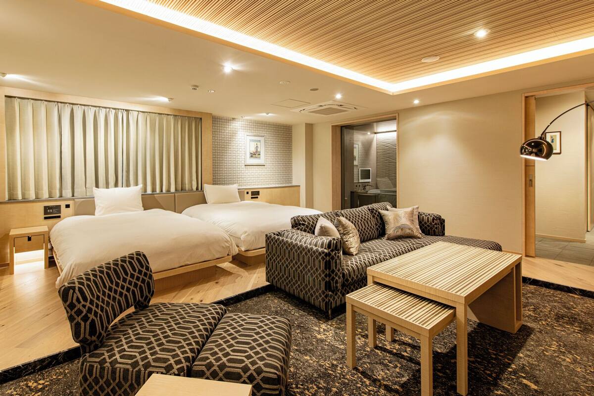 Ett modernt hotellrum med två sängar, en soffa, ett bord och ett litet skrivbord.