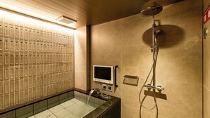 A modern bathroom with a glass-enclosed shower, a digital control panel, and a tiled wall.