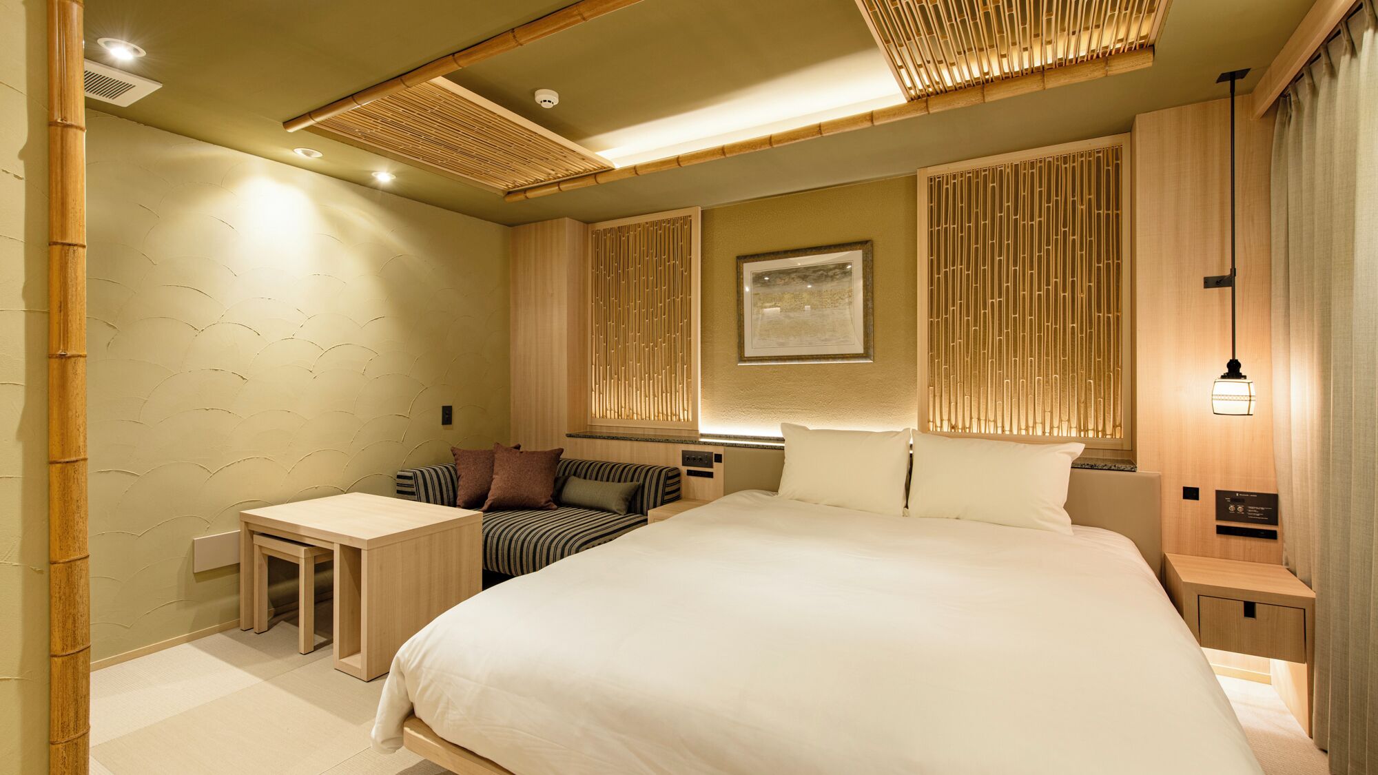 A modern hotel room with a large bed, a small desk, and a seating area.