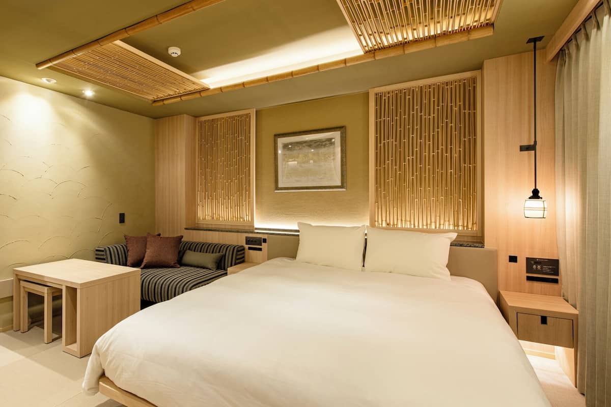 Ett modernt hotellrum med en stor säng, ett litet skrivbord och en sittgrupp.
