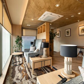 En modern inredning med ett träpanelat tak, en soffa, ett bord och en lampa.