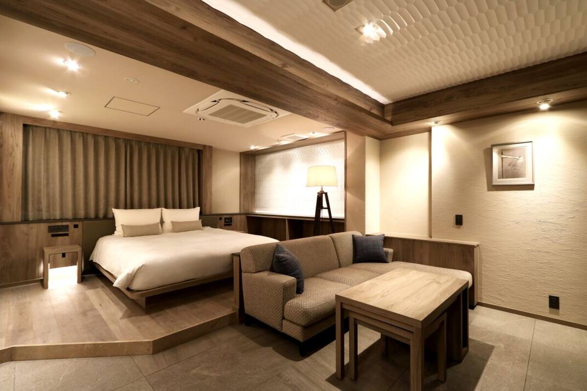 Ett hotellrum med en säng, soffa, bord och lampa.