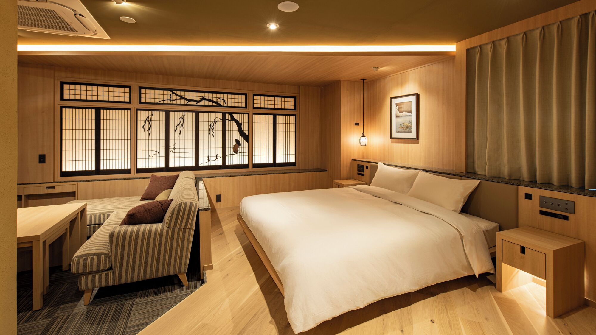 A traditional Japanese-style bedroom with a large bed, a sofa, and a futon.