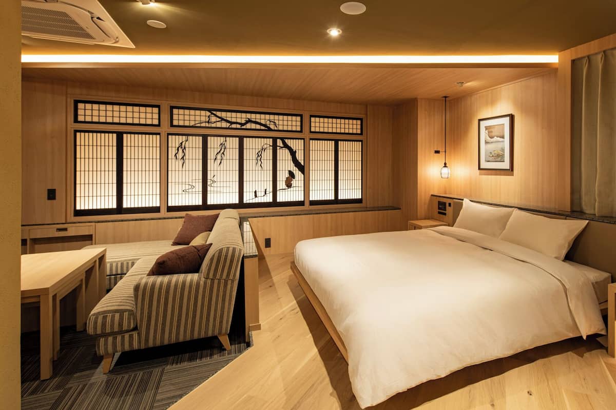 Ett traditionellt japanskt sovrum med en stor säng, en soffa och en futon.