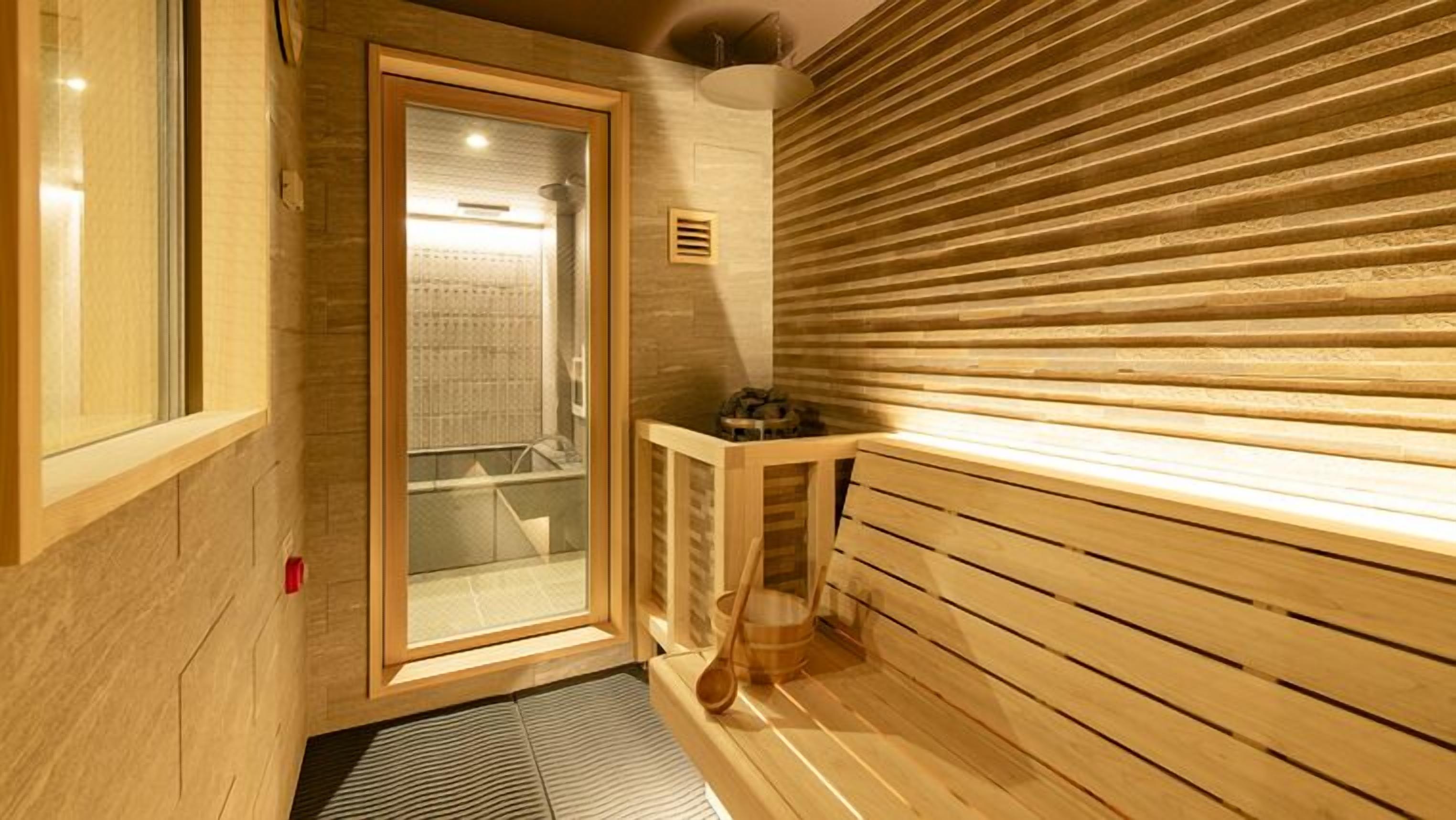 A sauna room with wooden benches, a glass door, and a small table with a bowl.