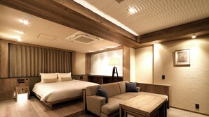 A hotel room with a bed, sofa, table, and lamp.