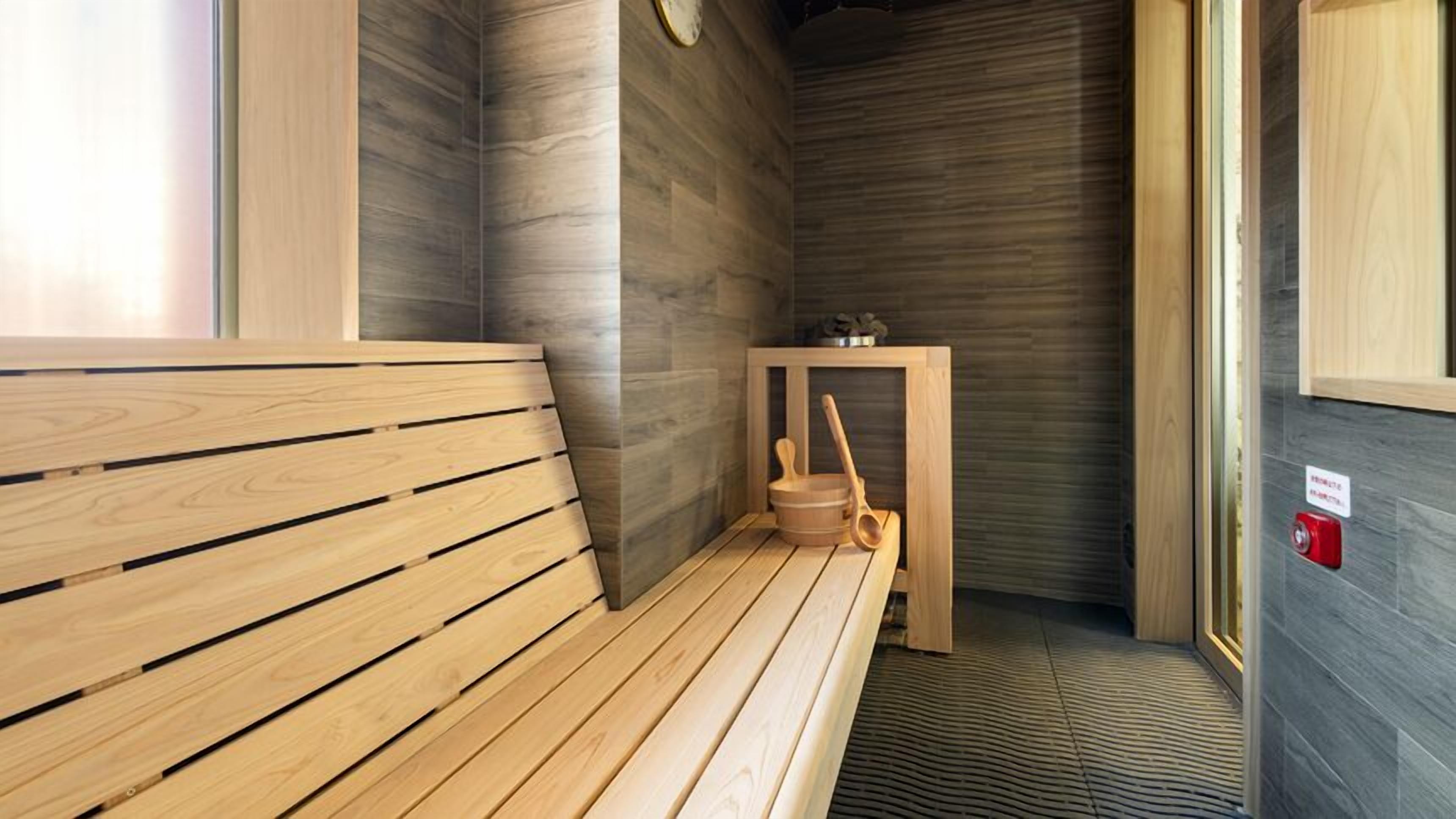A sauna room with wooden benches and a small table with a bucket and ladle.