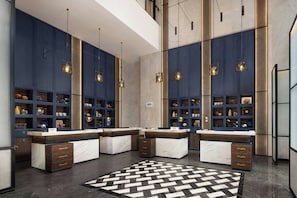 A modern kitchen with marble countertops, built-in shelving, pendant lighting, and a geometric patterned rug.