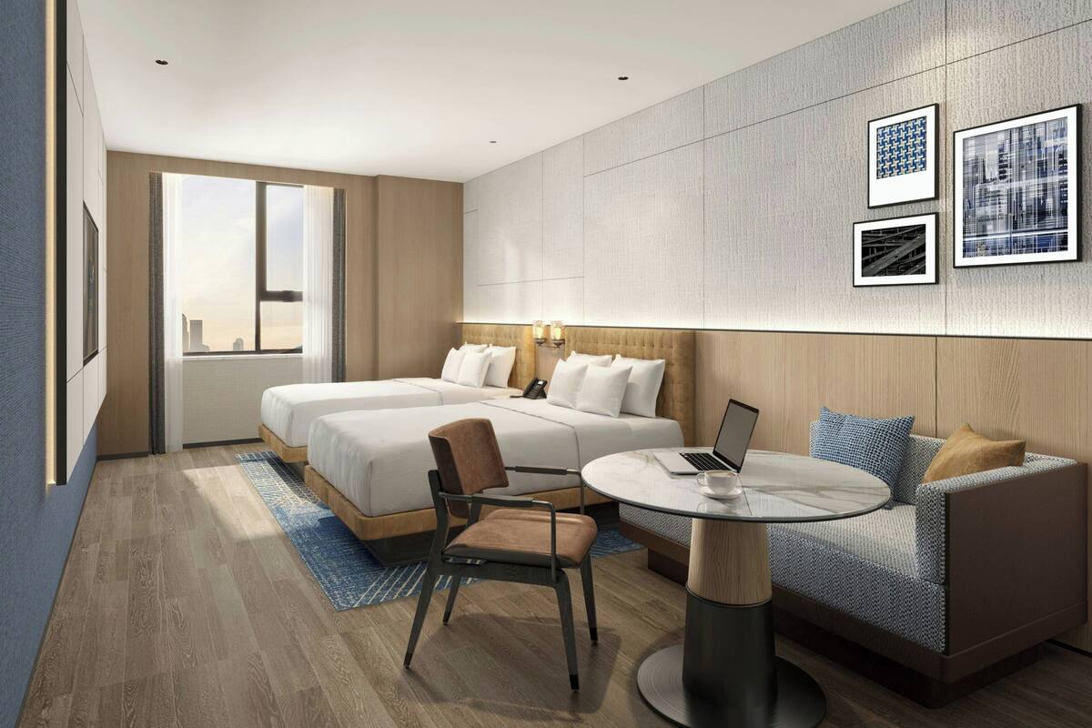 A modern hotel room with a large bed, a sofa, a round table, and a city view.