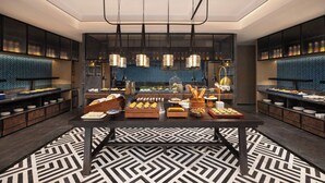 Un moderno buffet per la colazione con pavimento a motivi geometrici, lampadari a sospensione e un'area di servizio centrale.