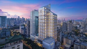 Un hotel di grandi dimensioni con una facciata in vetro moderna, diversi piani e una segnaletica ben visibile.