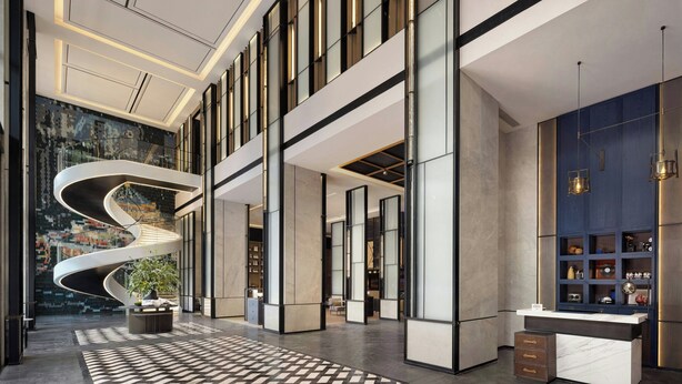 Una hall d'albergo moderna con una scala a chiocciola, una reception e un'ampia finestra.