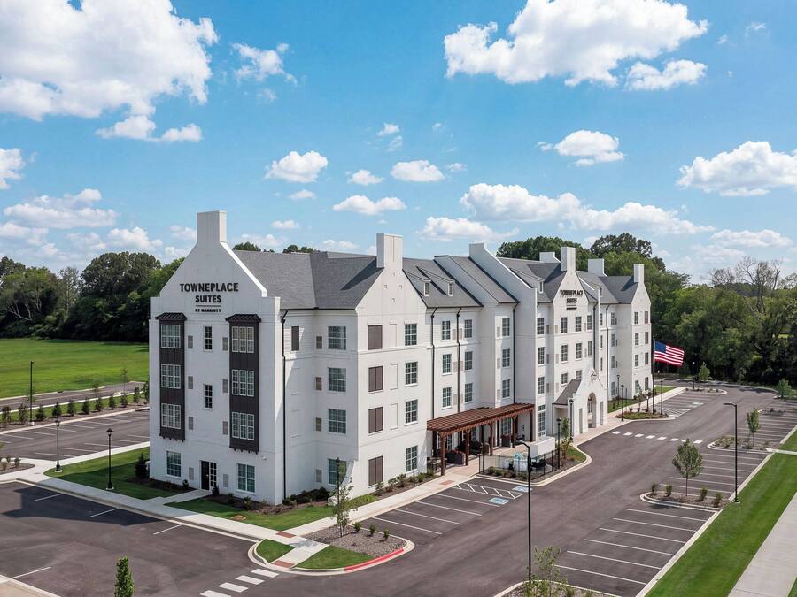 Een meerhoog hotel met een opvallend 'Towneplace Suites by Marriott' bord, een parkeerplaats en een vlag.