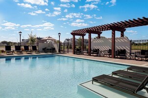 Una piscina con sillas de descanso y una pérgola.