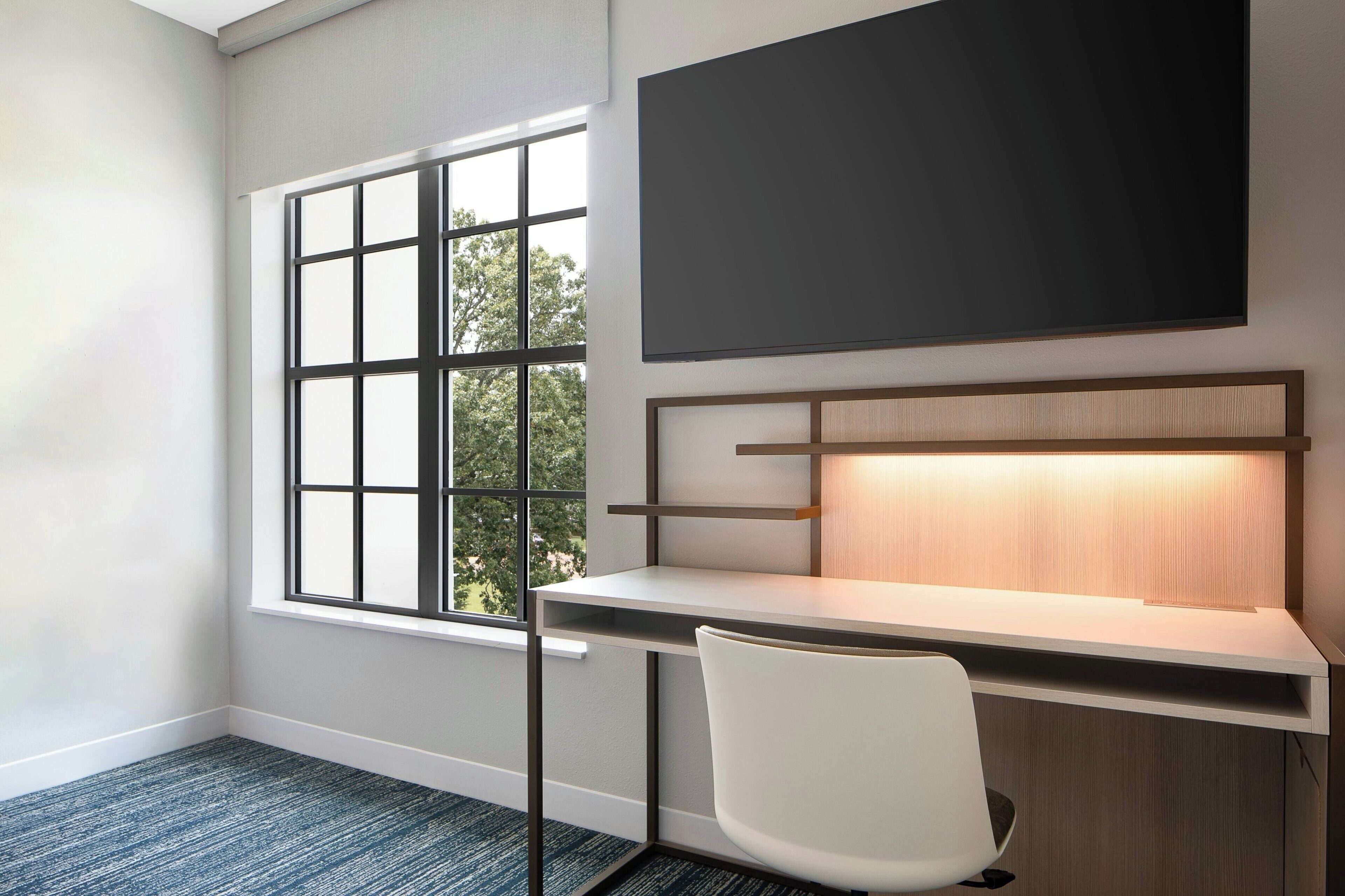Un espacio de oficina moderno con un escritorio, una silla y un amplio ventanal.