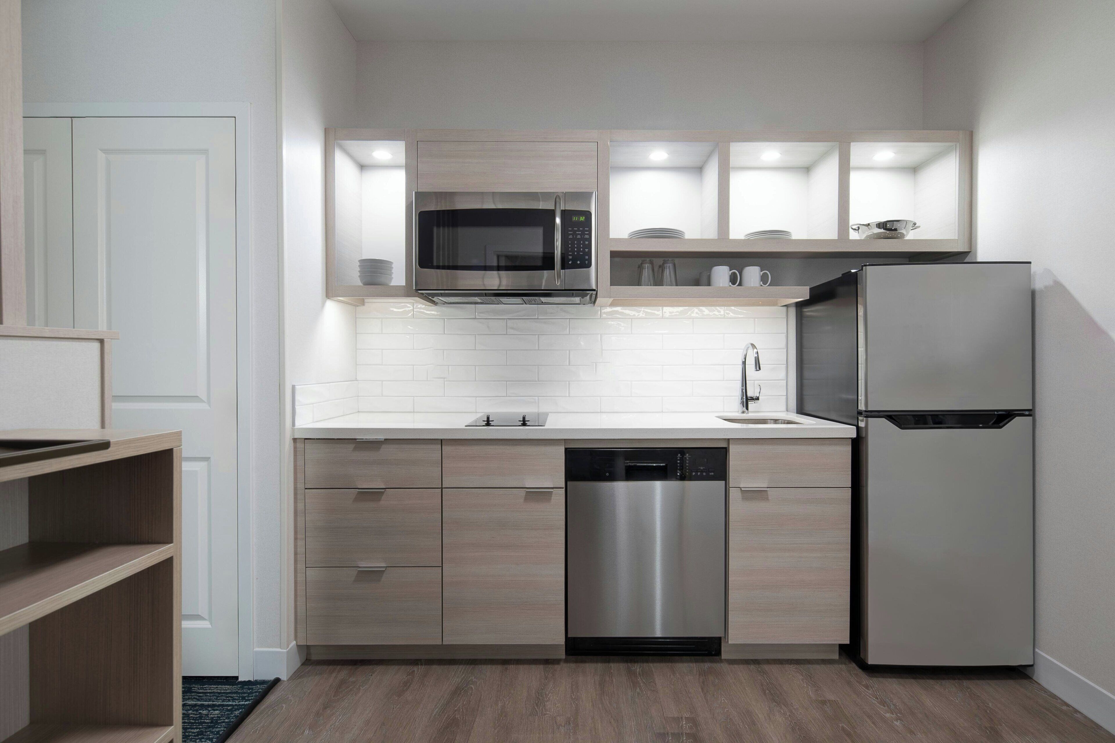 A modern kitchen with a stainless steel refrigerator, built-in dishwasher, and a microwave above the sink.