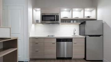 A modern kitchen with a stainless steel refrigerator, built-in dishwasher, and a microwave above the sink.