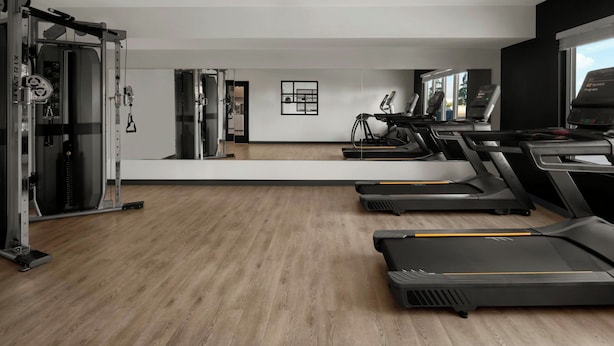 A gym with treadmills, a weight machine, and a mirror. - StudioRes by Marriott Mesa (Mesa)
