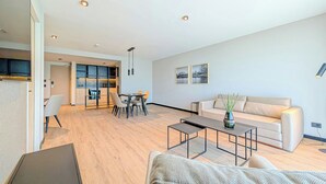 A modern living room with a sofa, coffee table, and dining area. - Brickton, Rosario, Apartments By Marriott Bonvoy (Rosario)