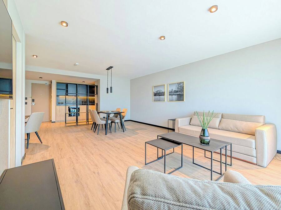 A modern living room with a sofa, coffee table, and dining area.