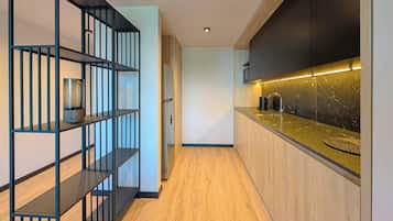 A modern kitchen with wooden flooring, black shelving, and a granite countertop.
