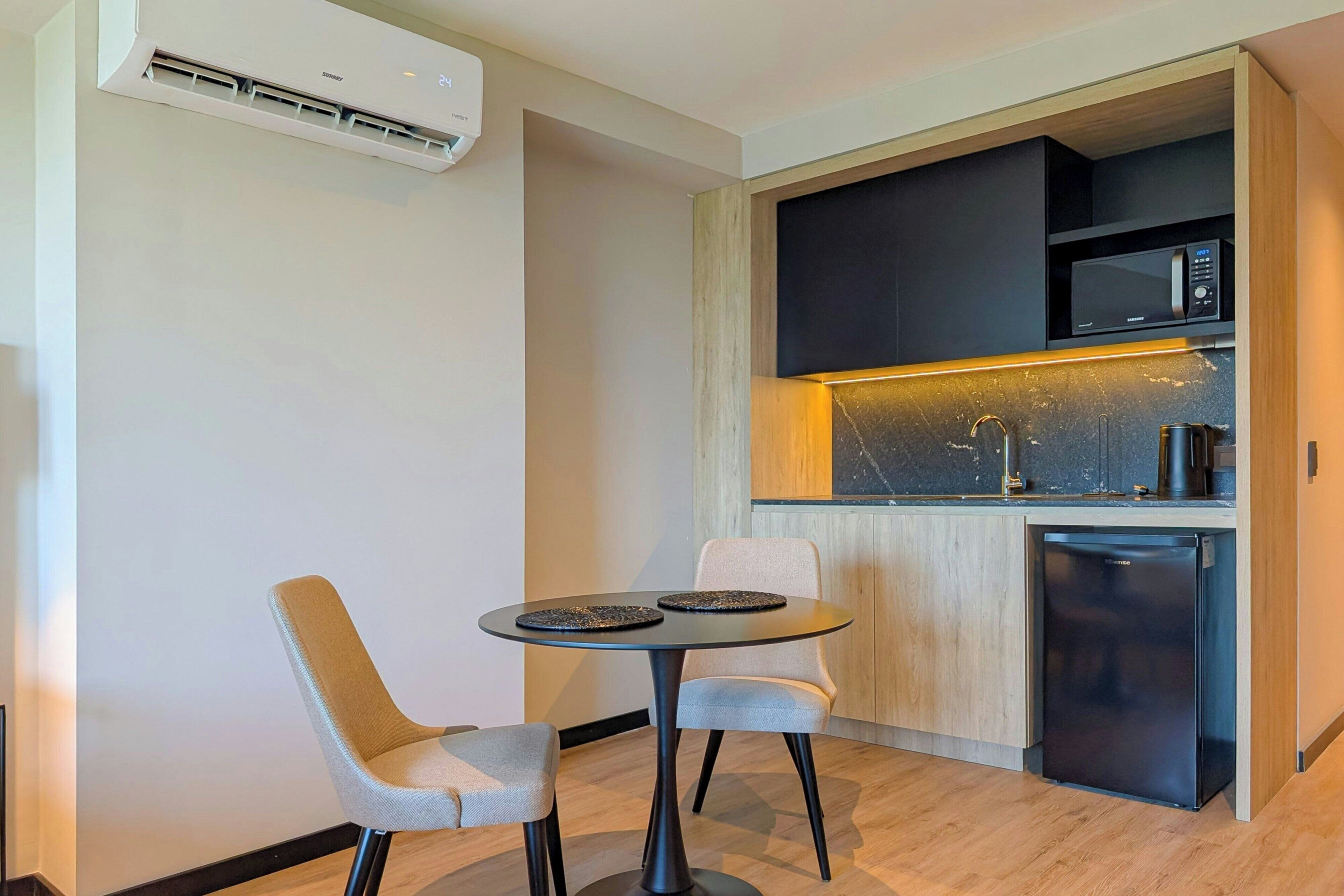 Une cuisine moderne équipée d’un four à micro-ondes encastré, d’une machine à café et d’un réfrigérateur compact.