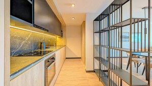 A modern kitchen with a marble countertop, stainless steel appliances, and a wooden floor. - Brickton, Rosario, Apartments By Marriott Bonvoy (Rosario)