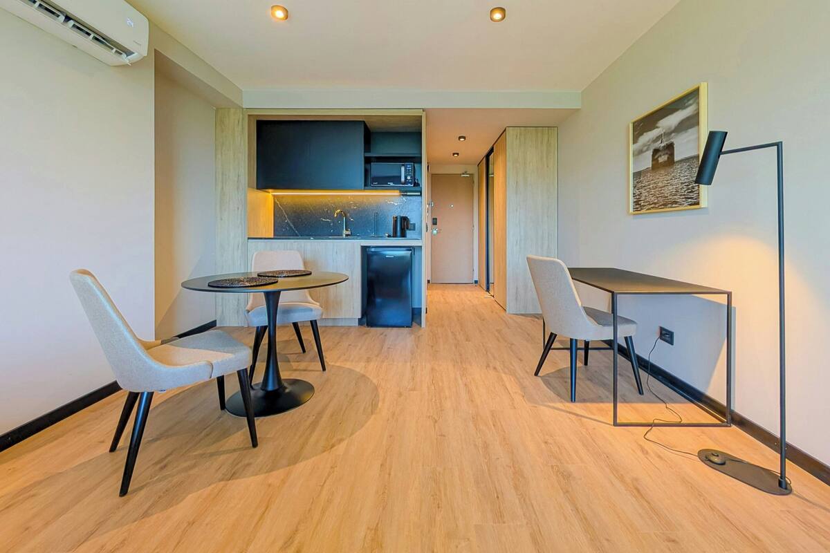A modern kitchen with a microwave, sink, and coffee machine. There is a dining area with two chairs and a table.