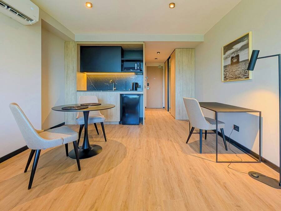 Cocina moderna con microondas, fregadero y cafetera. Comedor con dos sillas y una mesa.