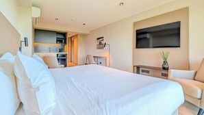 A hotel room with a large bed, a desk with a chair, a TV, and a kitchenette. - Brickton, Rosario, Apartments By Marriott Bonvoy (Rosario)