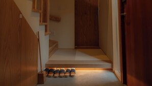 A hallway with a wooden staircase, a banner with 'ZIPANG' text, and a row of shoes at the bottom.