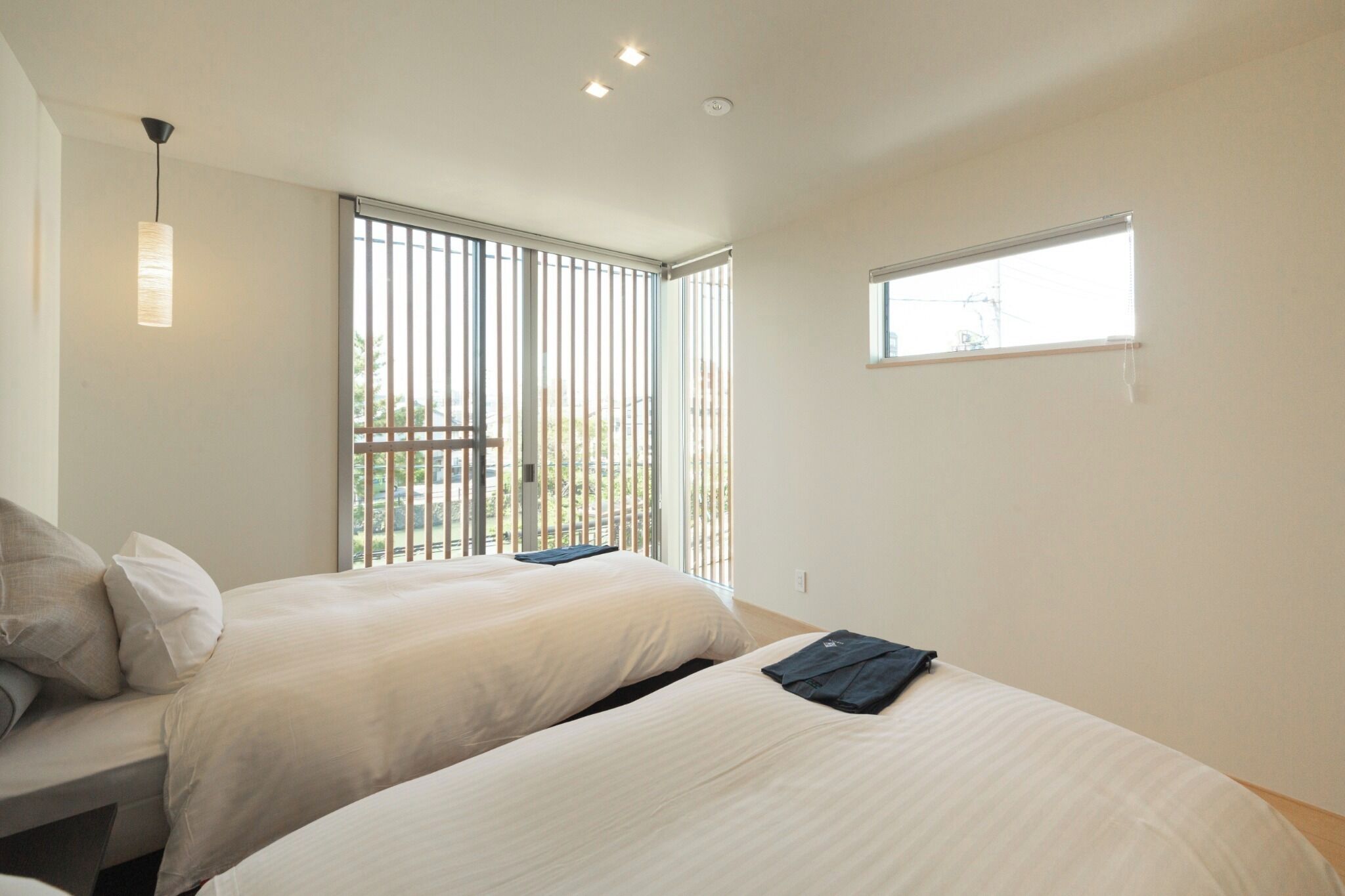 A hotel room with two beds, a window, and a view of the outdoors.