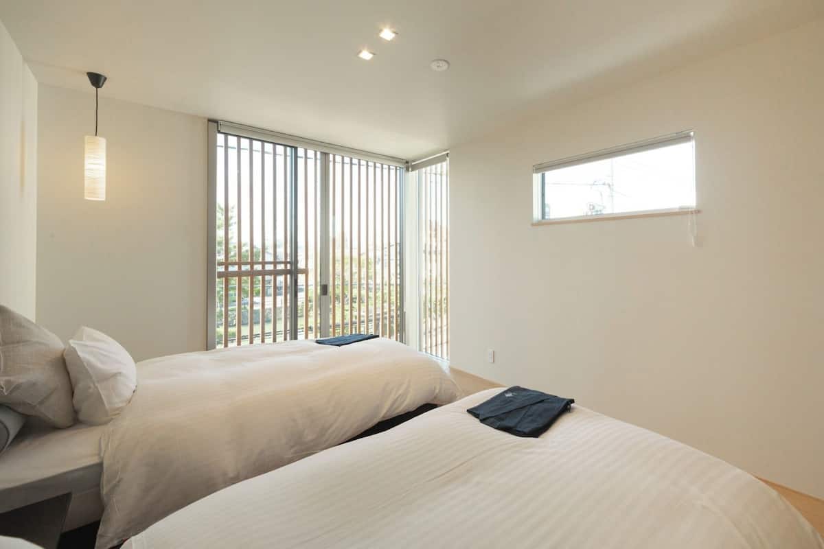 A hotel room with two beds, a window, and a view of the outdoors.