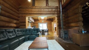 A log cabin interior with a leather sofa, a wooden coffee table, a fireplace, and a dining area. - Tabino Teitaku Realiser Zao (Zao)