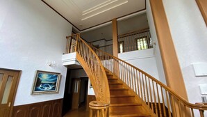 A wooden staircase with a handrail, a framed painting on the wall, and a door at the bottom. - Tabino Teitaku Realiser Zao (Zao)