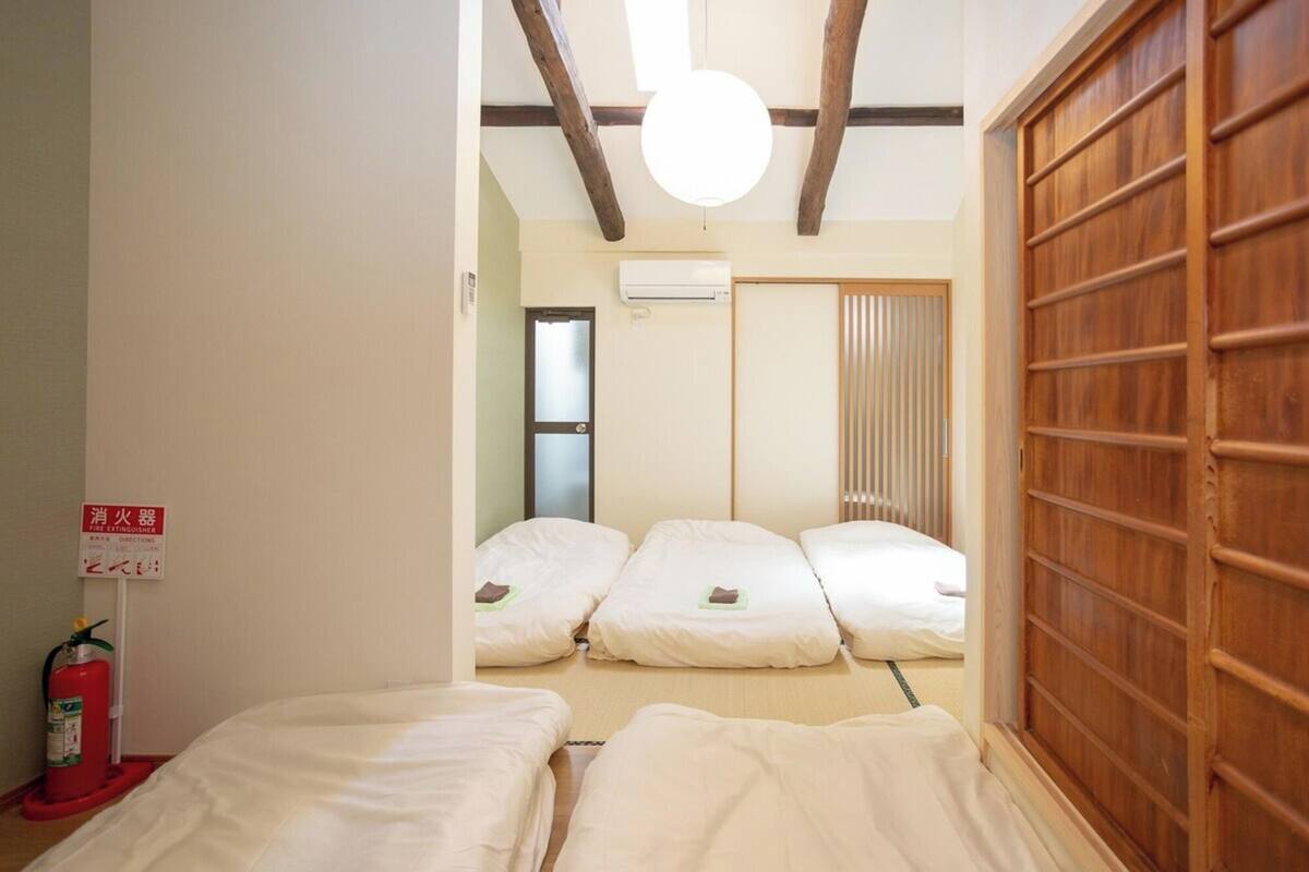 A room with three beds, a fire extinguisher, and a sliding door.