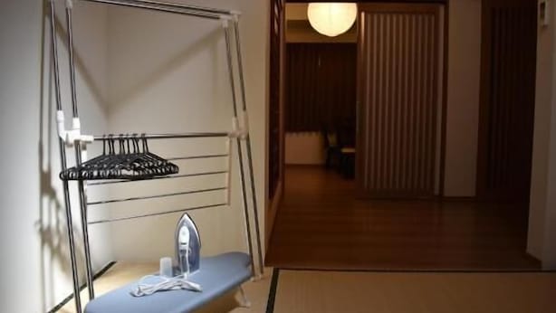 A room with a built-in ironing station, a hanging rack, and a traditional Japanese sliding door. - Enraku (Kyoto)