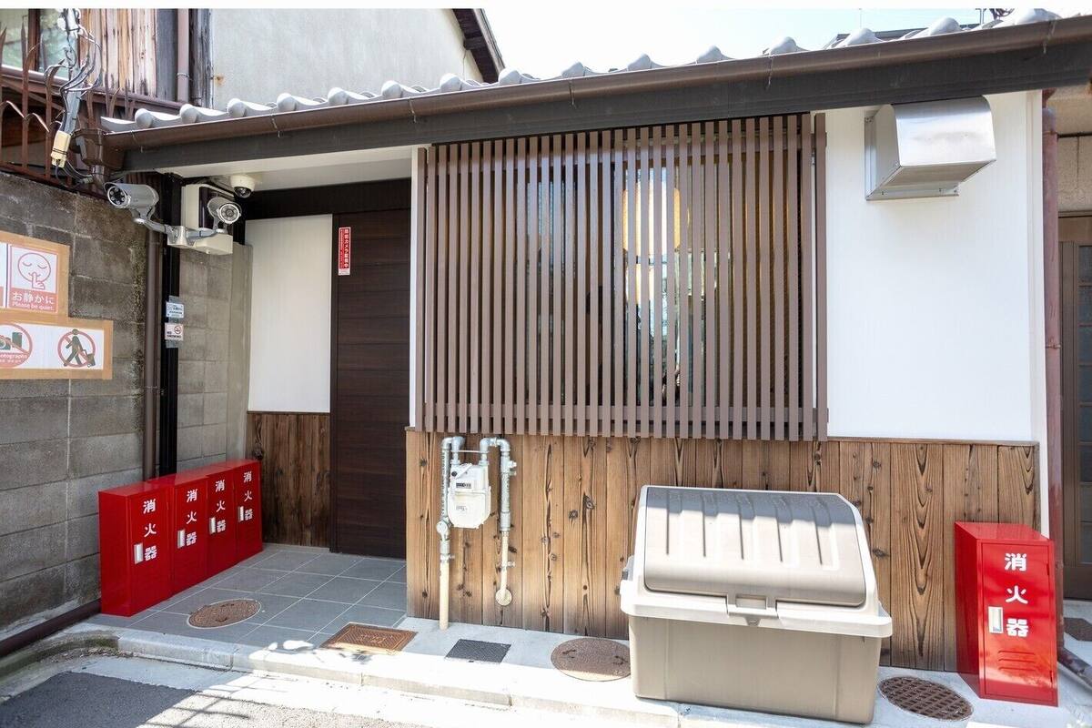 A building entrance with a wooden door, a metal gate, and a small outdoor seating area.