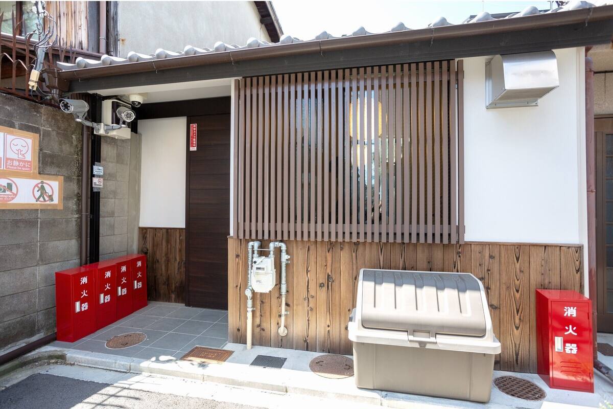 A building entrance with a sliding door, a barbecue grill, and red fire extinguishers.