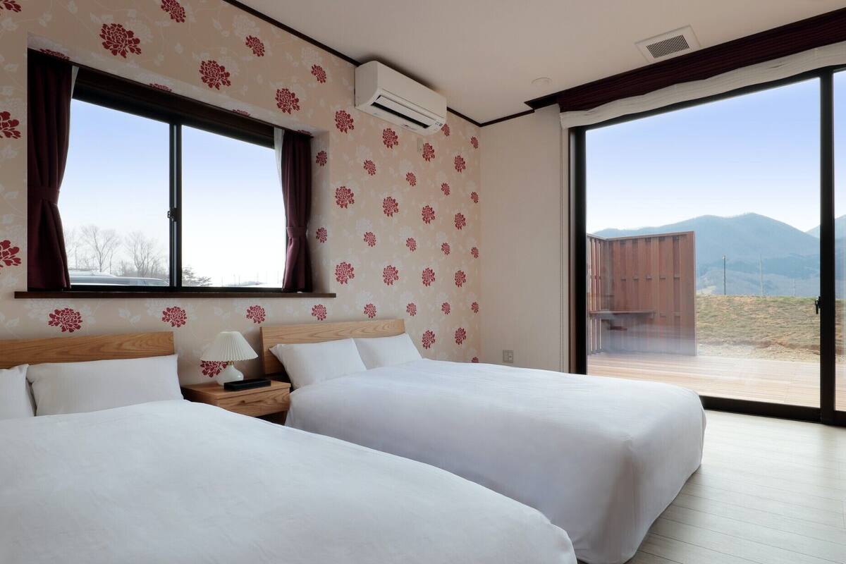 A room with two beds, a window, and a view of mountains.