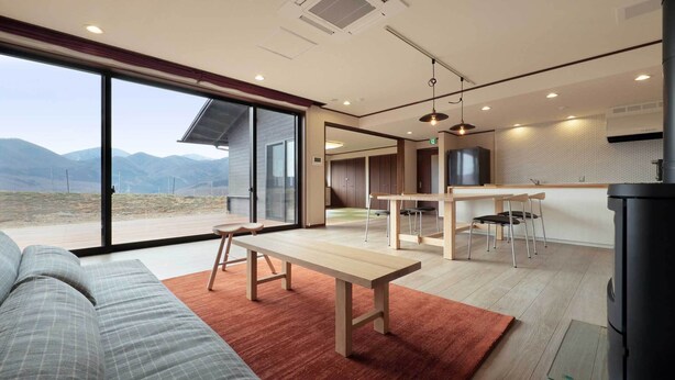A modern interior with a dining area, a sofa, and a view of the outdoors.