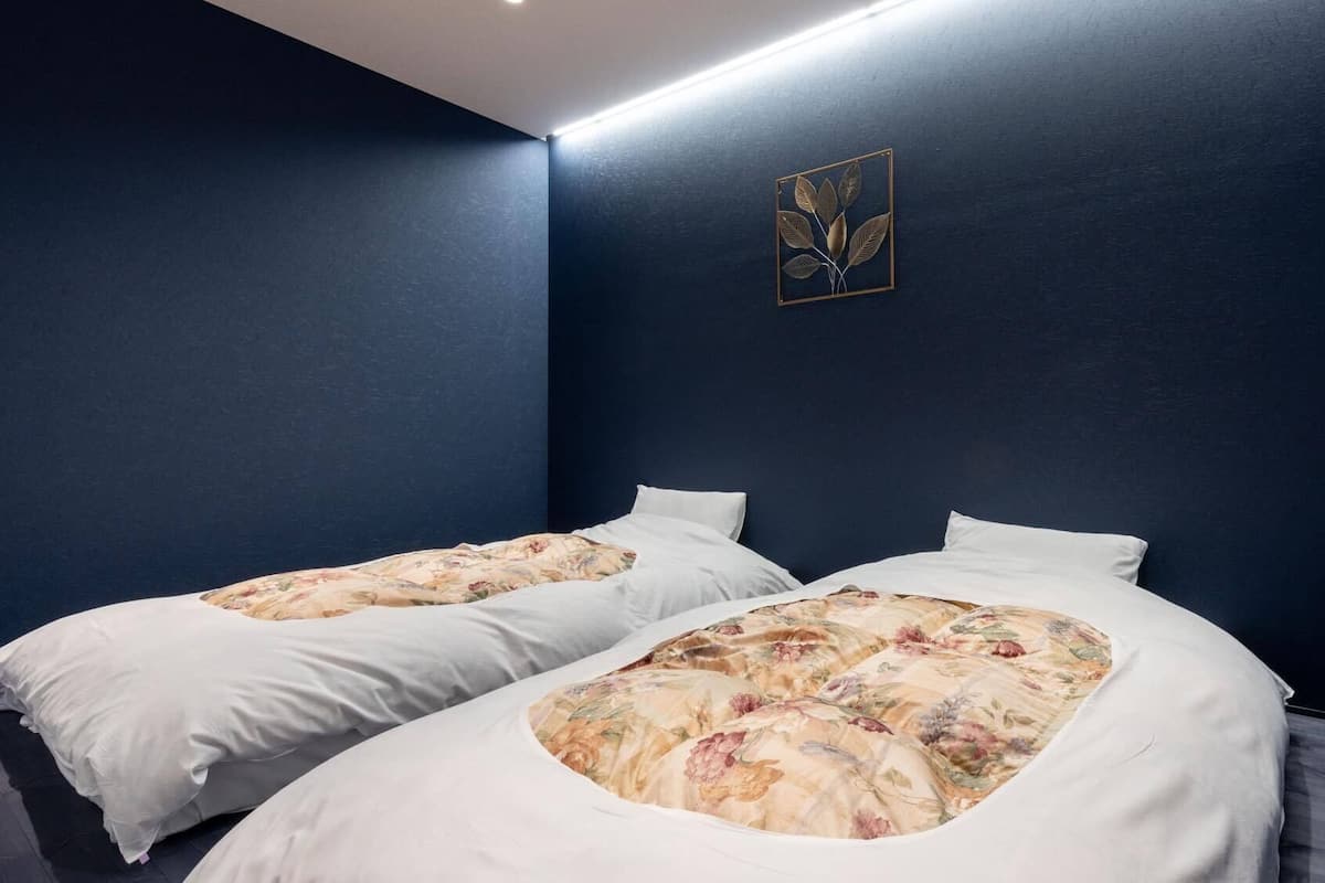 Ein Zimmer mit zwei Betten, dunklen Wänden und einer Deckenlampe.
