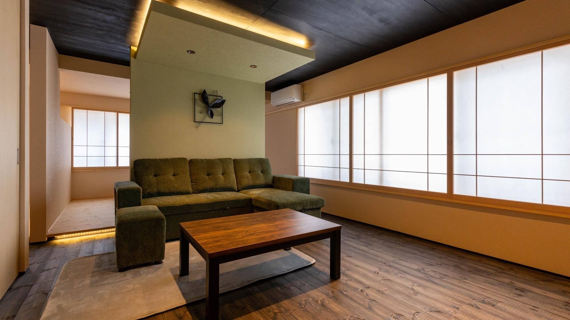 Uma sala de estar moderna com um sofá seccional, uma mesa de centro de madeira e janelas amplas.