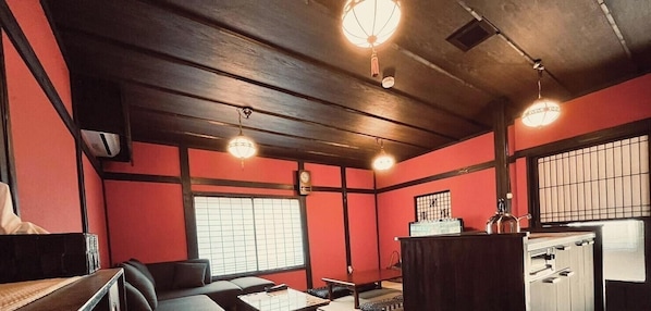 Ein Zimmer mit Holzboden, einer traditionellen japanischen Schiebetür, einem kleinen Tisch und einer Theke mit einem Wasserkocher.