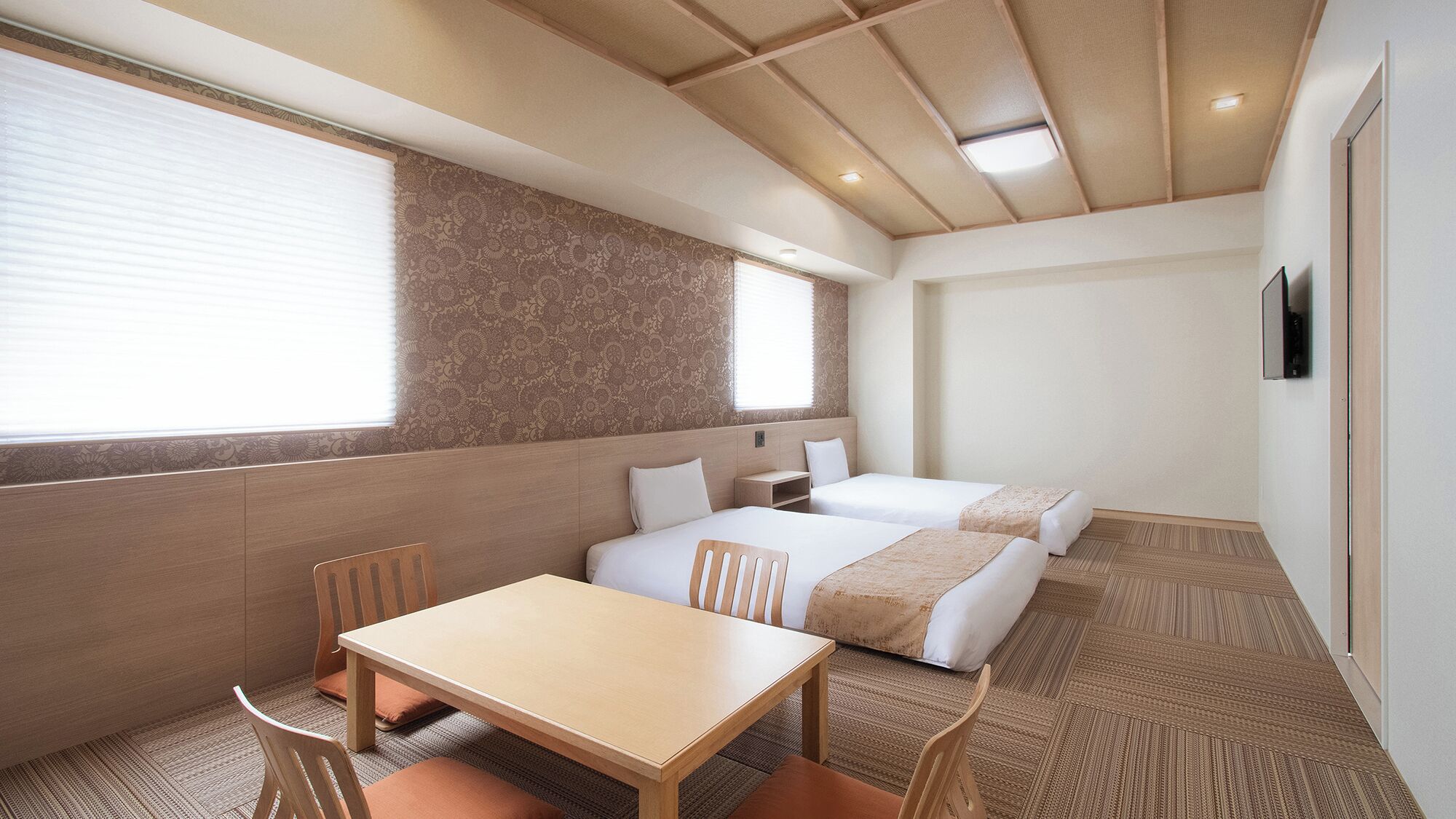 Ein Hotelzimmer mit Holzboden, zwei Betten, einem Tisch und Stühlen.