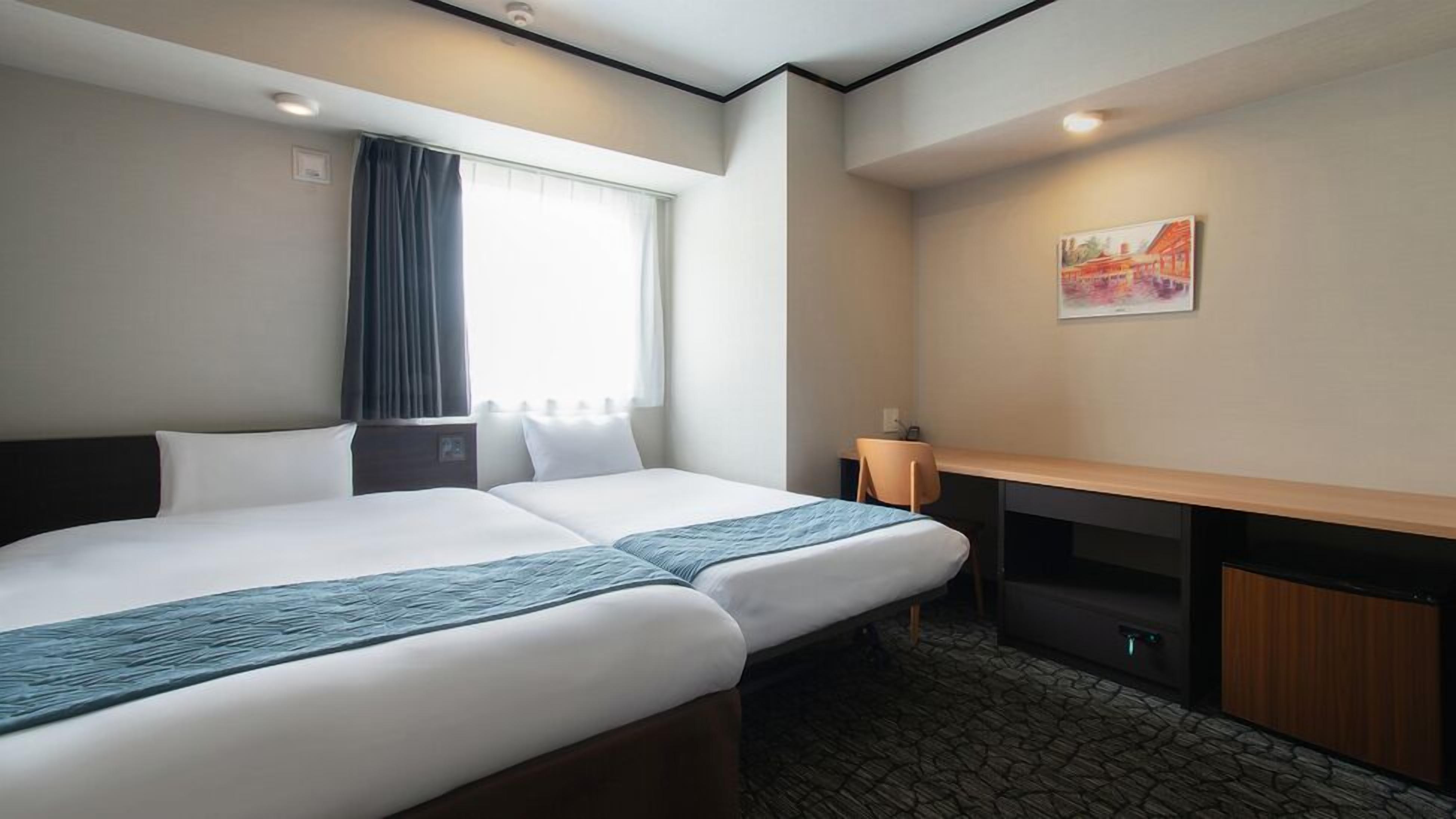 Ein Hotelzimmer mit zwei Betten, einem Schreibtisch, einem Stuhl, einem Fenster mit Vorhängen, einem Bild an der Wand und einem Boden mit Steinmuster.