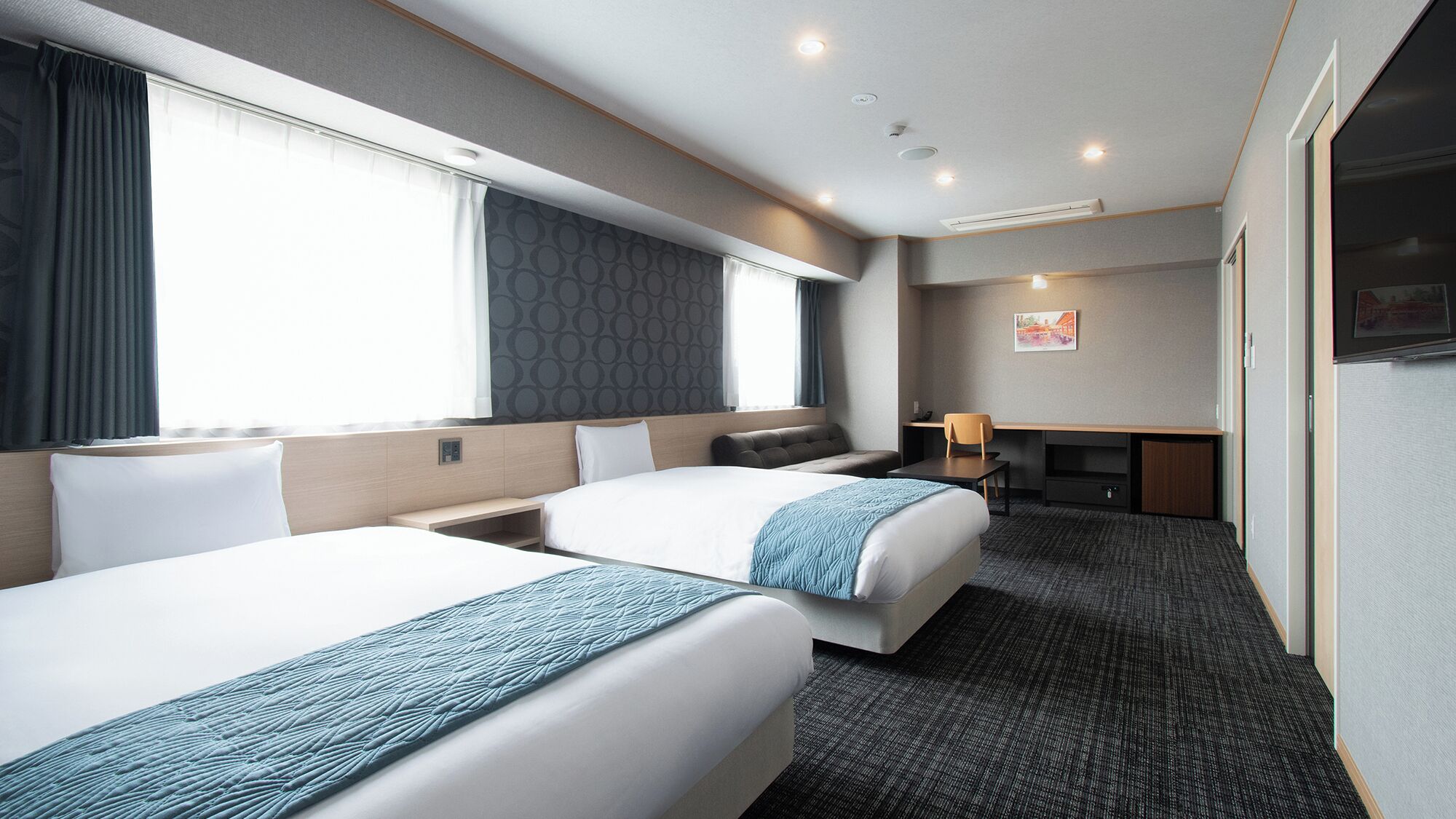 Ein Hotelzimmer mit zwei Betten, einem Schreibtisch, einem Stuhl und einem Fernseher.